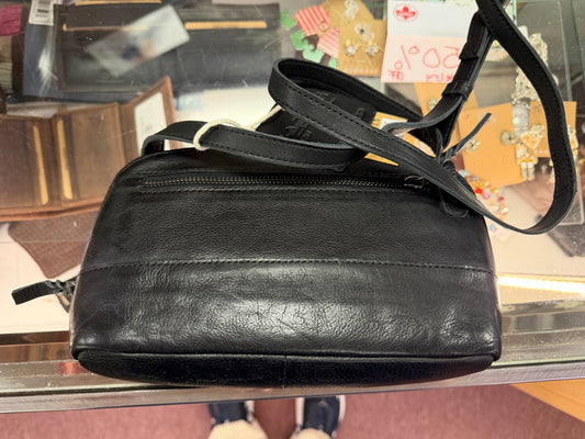 Black leather handbag on a glass surface with a blurred background